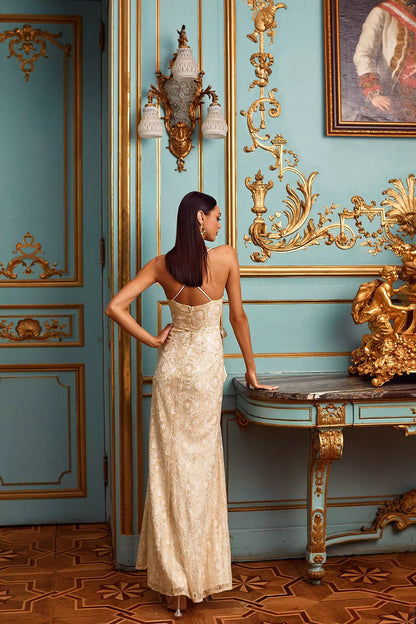 A woman in a gold dress standing in a blue room.