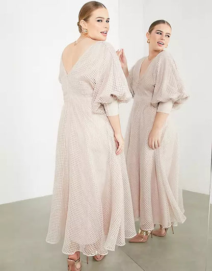 A woman is standing in front of a mirror wearing a beige dress.