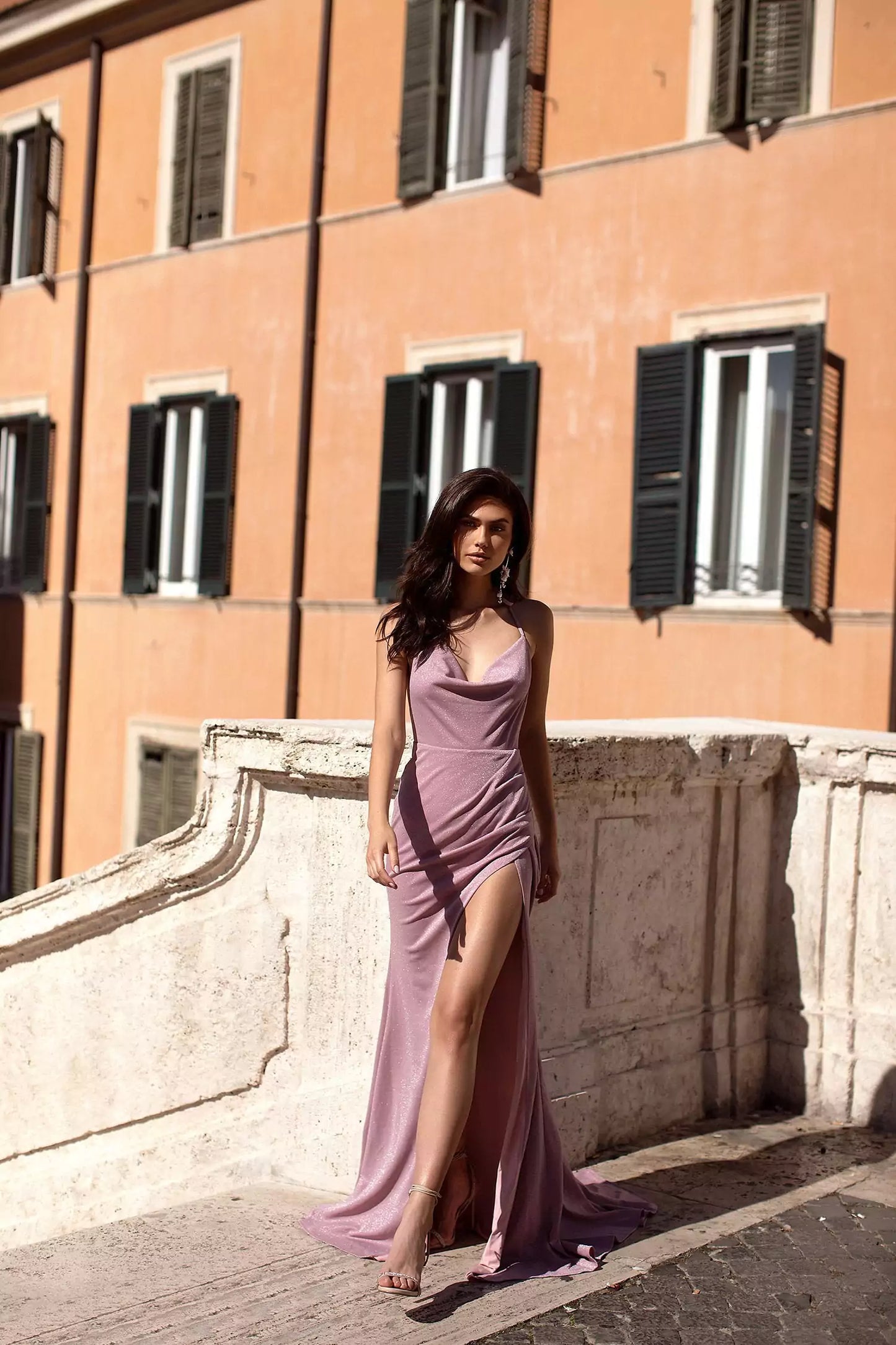 A woman in a purple dress posing in front of a building.