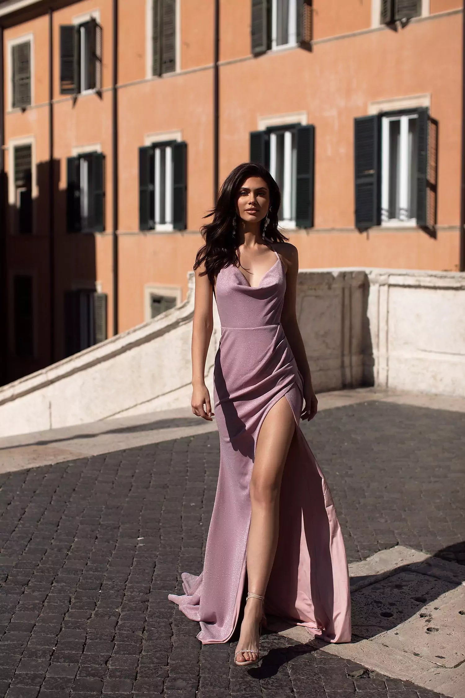 A woman in a lavender dress posing in front of a building.