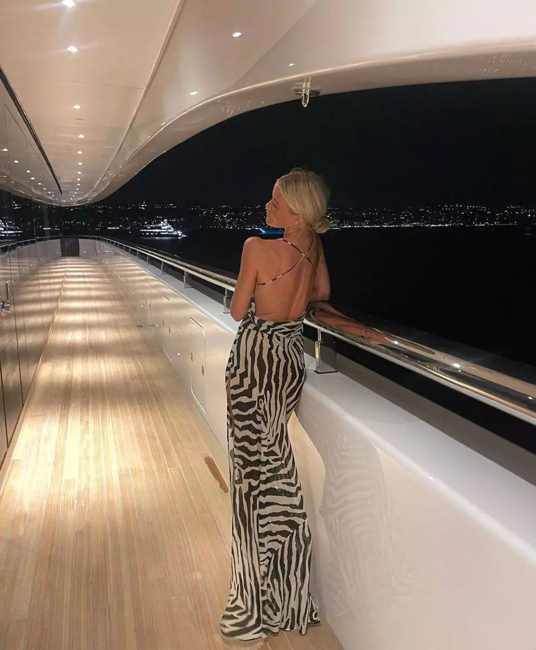 A woman in a zebra print dress standing on the deck of a yacht.