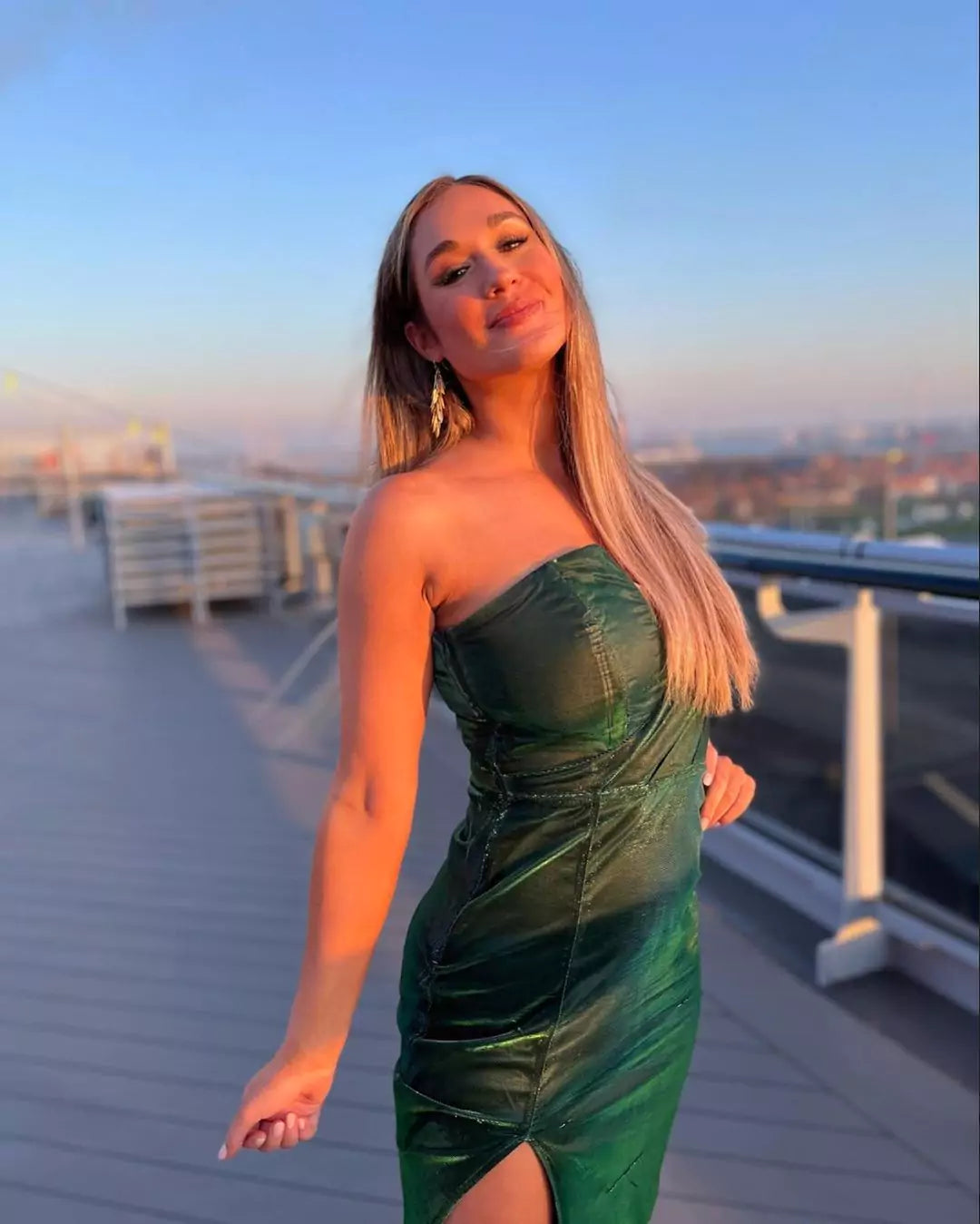 A woman in a green dress posing on a rooftop.