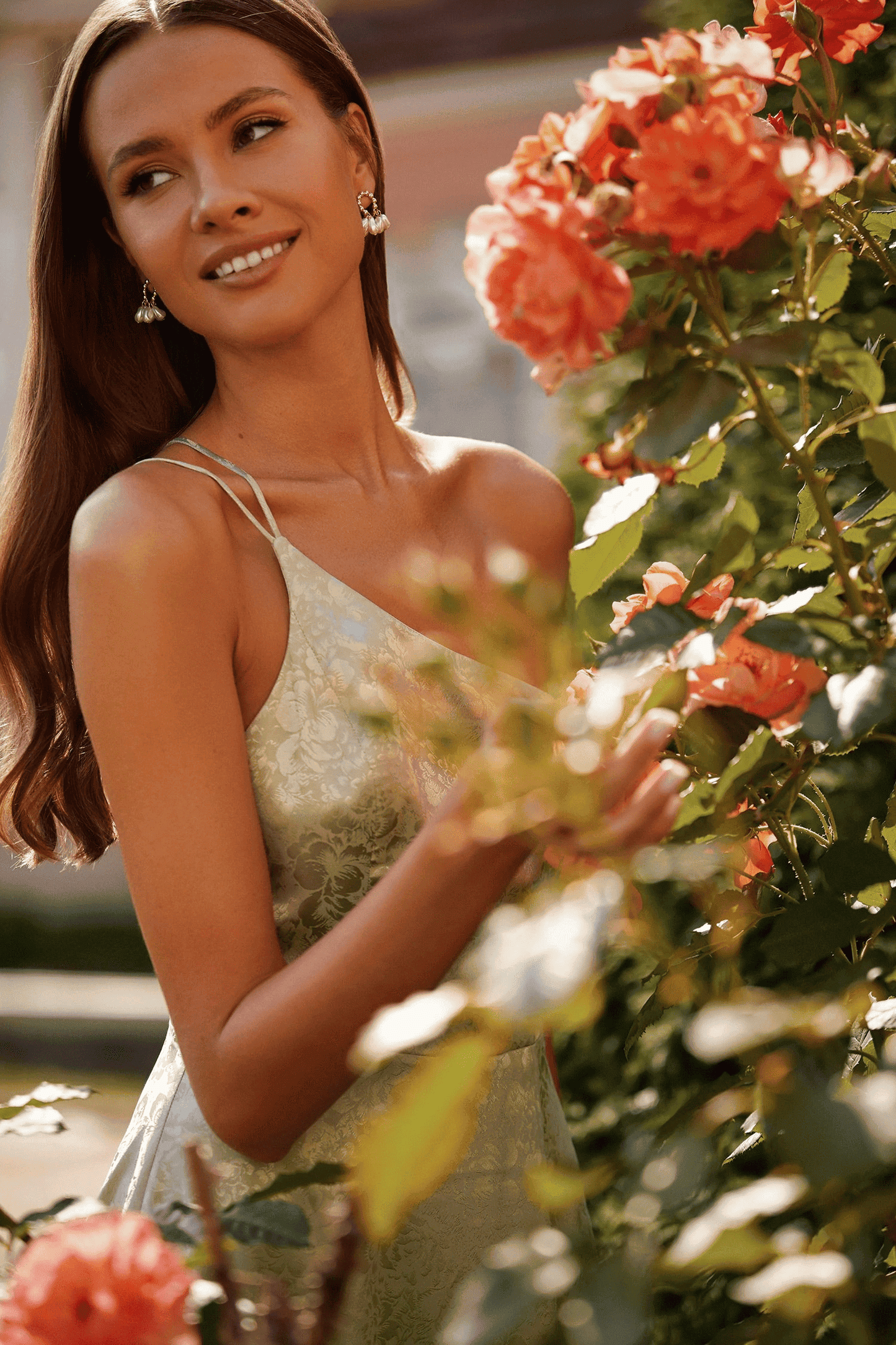 A beautiful woman in a green dress posing in front of roses.