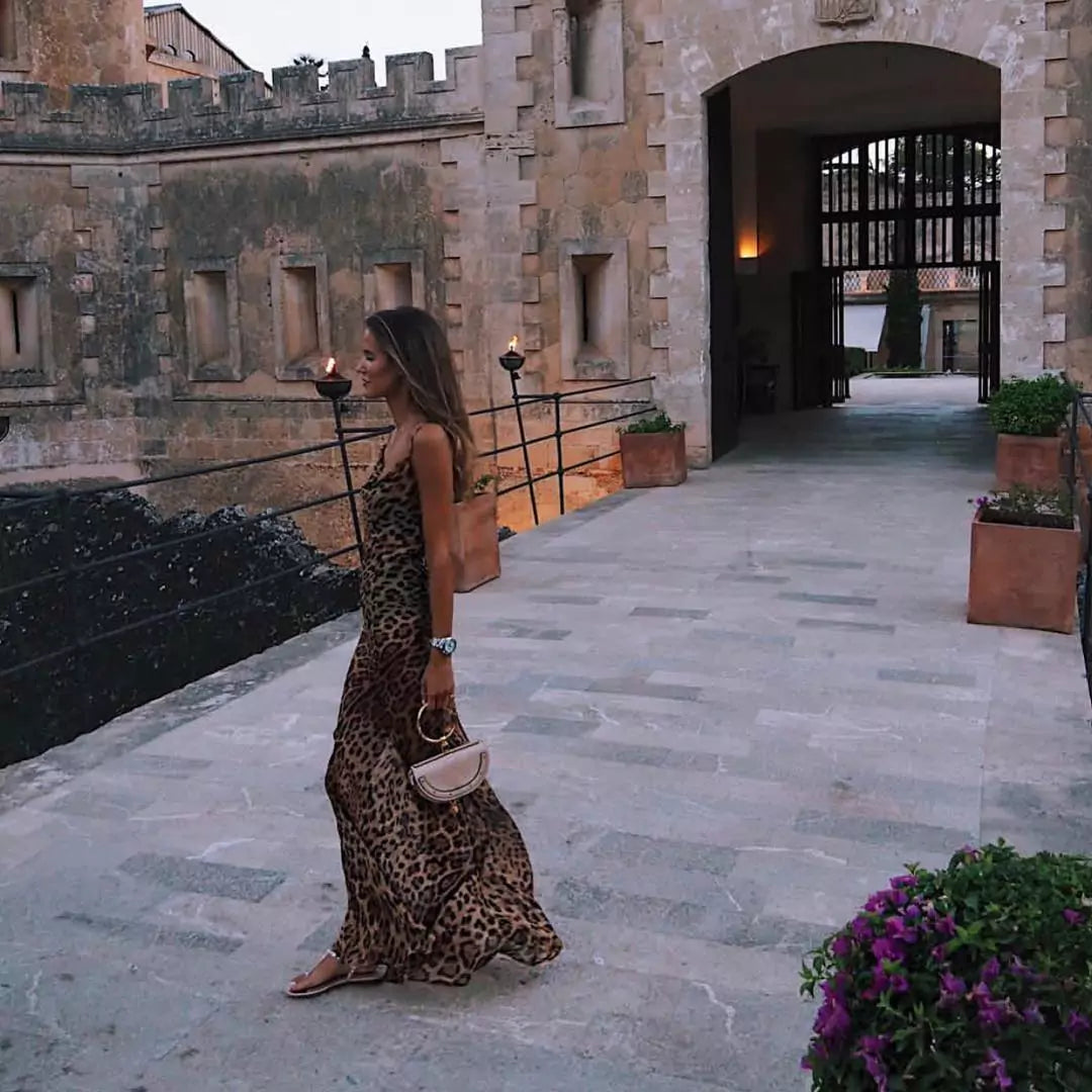 A woman wearing a leopard print dress in front of a castle.