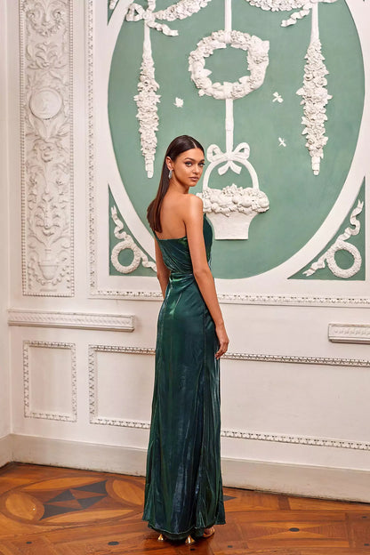 A woman in an emerald gown posing in front of a wall.