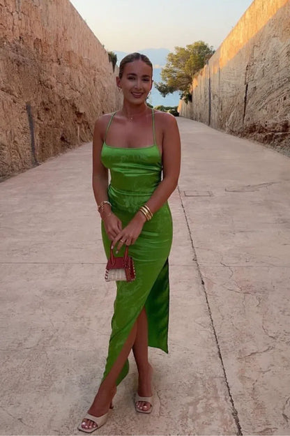 A South African wedding guest in a green slip dress is posing for a picture.