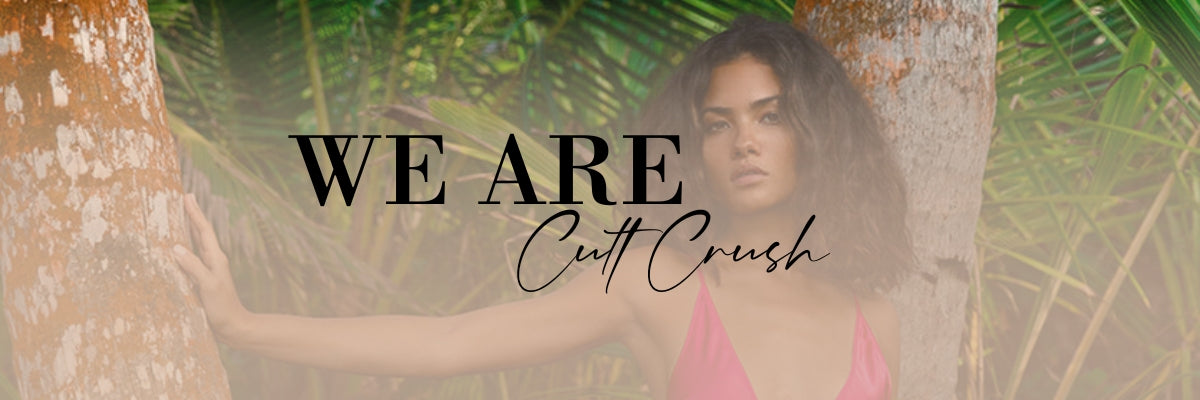 A woman in a pink slip dress leaning against a tree in background with we are Cult Crush.