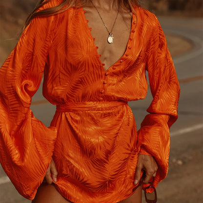 A woman in an orange dress is standing on the side of the road.