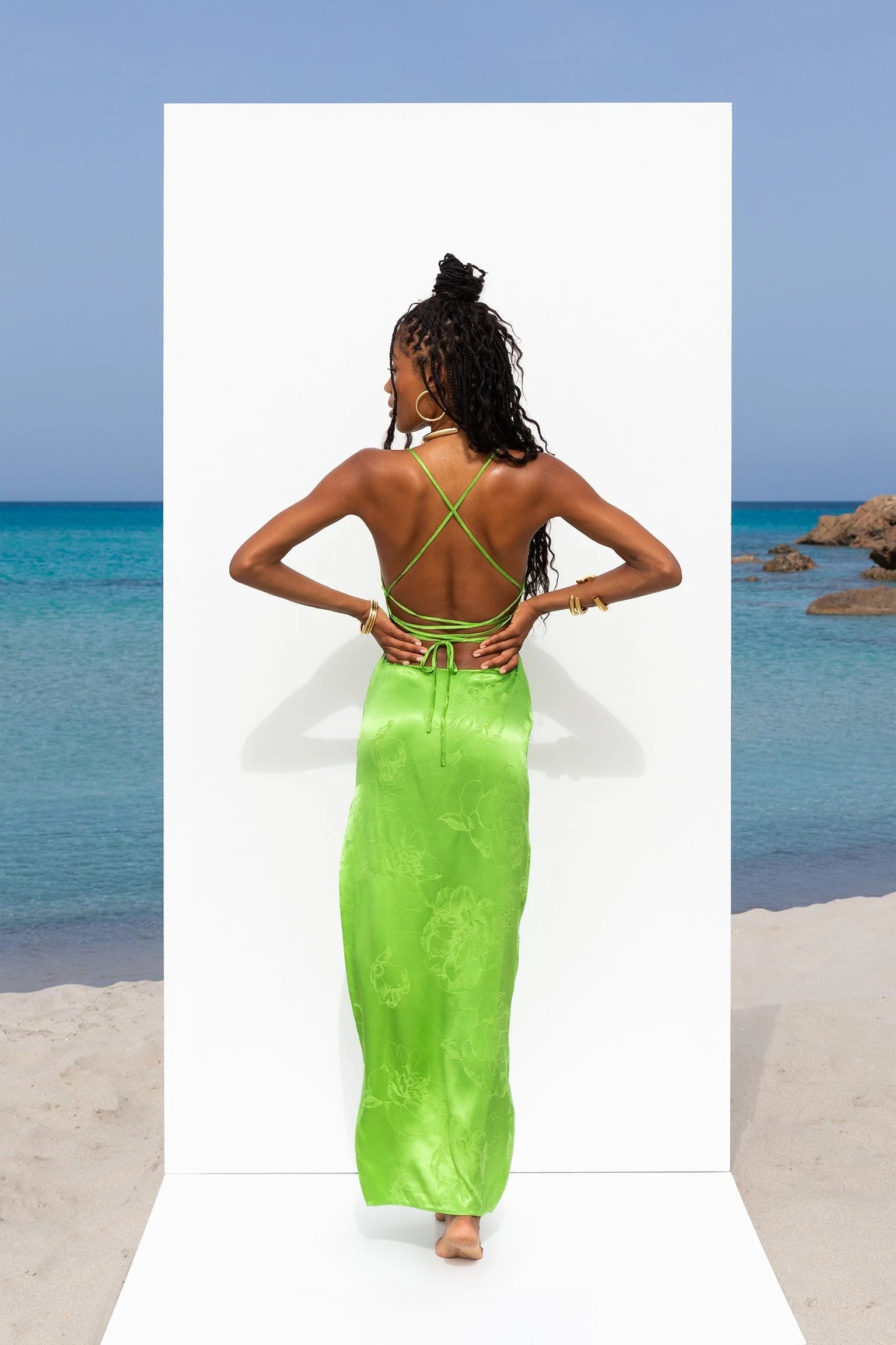 A woman in a green dress standing on the beach.
