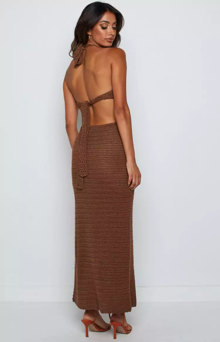 The back view of a woman wearing a brown knitted maxi dress.