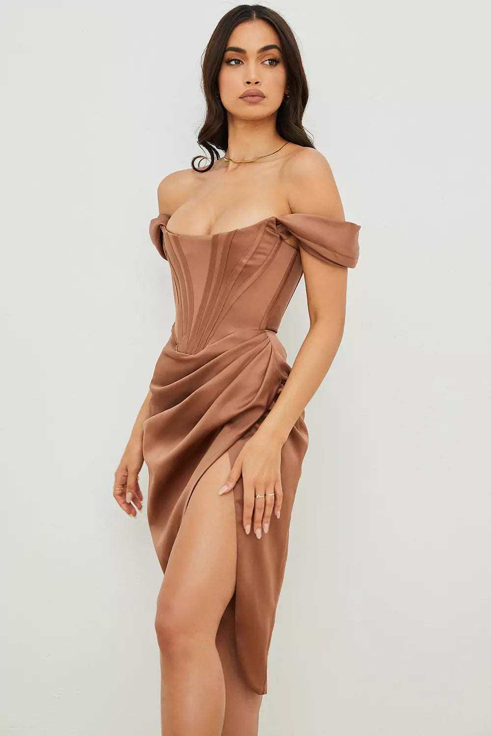 The model is wearing a brown satin dress with a high slit.