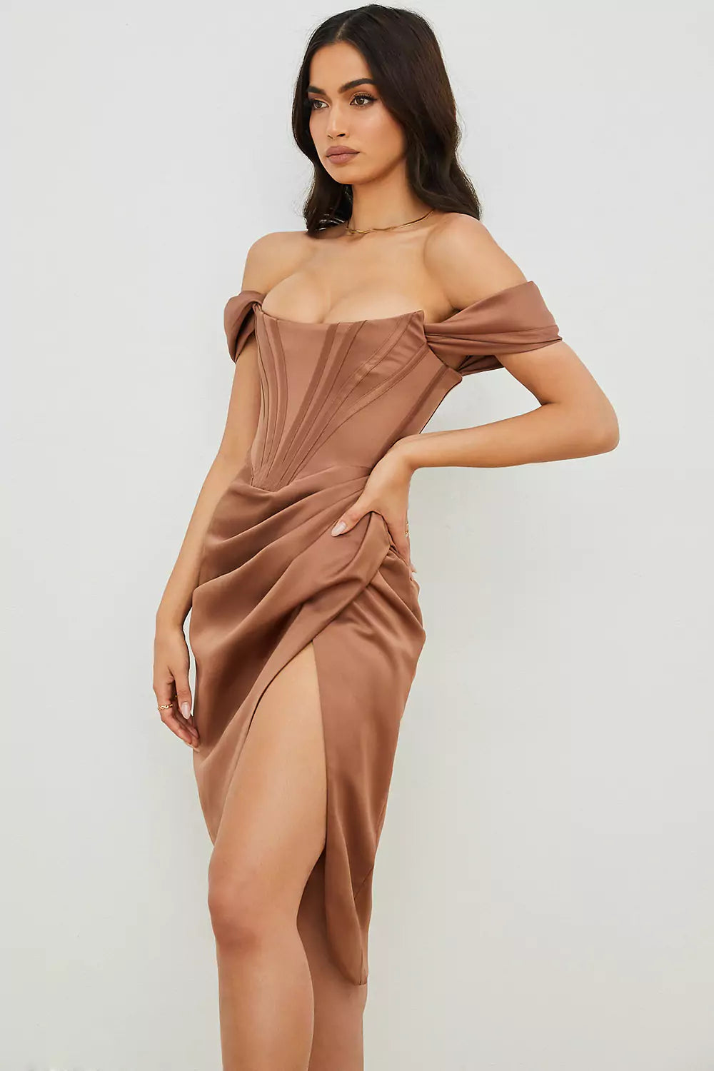 The model is wearing a brown satin dress with a slit.