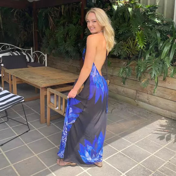 A woman in a blue and black maxi dress standing on a patio.