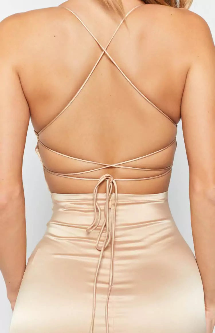 The back view of a woman in a nude satin dress.