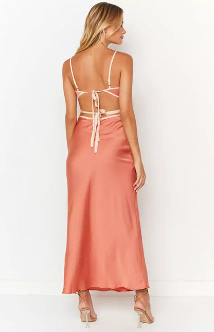 The back view of a woman wearing a peach satin midi dress.