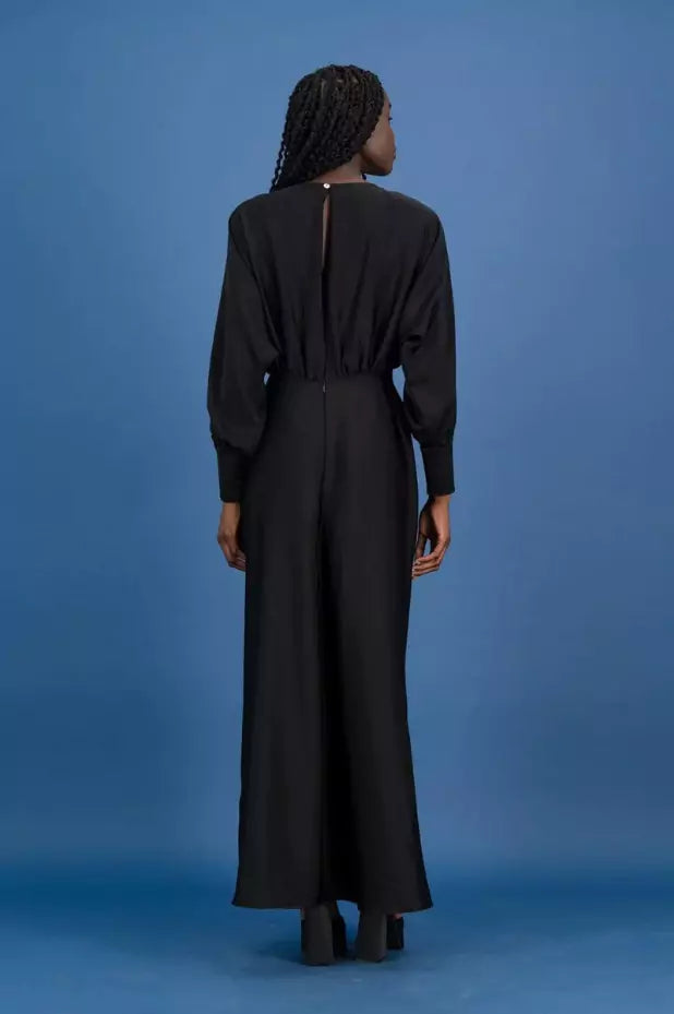 The back view of a woman wearing a black maxi dress.