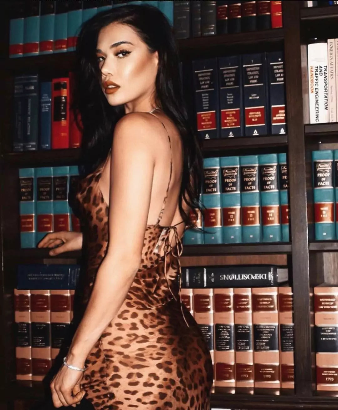 A woman in a leopard print dress making a style statement in front of bookshelves.
