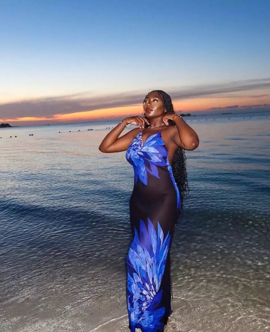 A boho-chic woman in a blue maxi dress standing on the beach at sunset in South Africa.