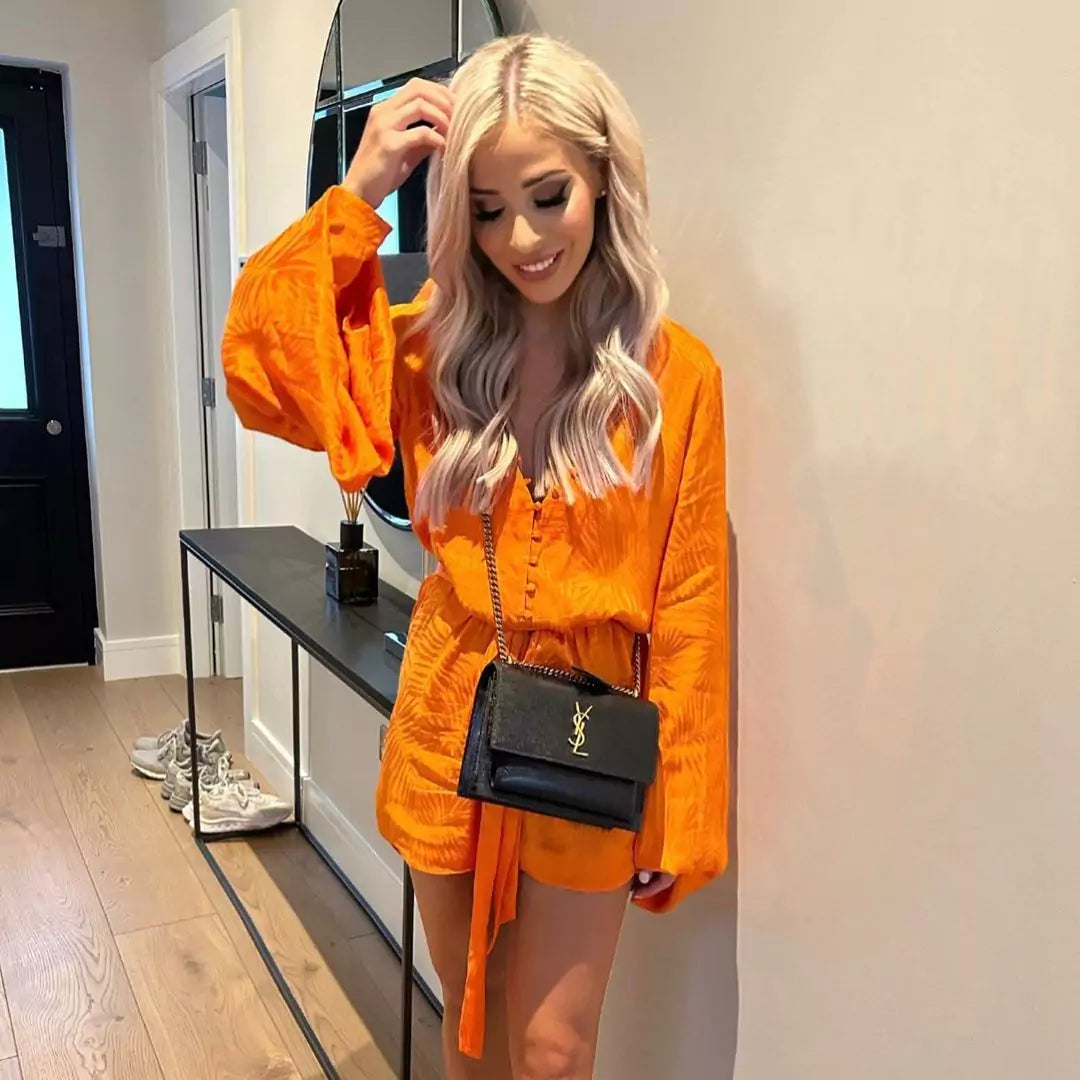 A woman in an orange romper posing in front of a mirror.