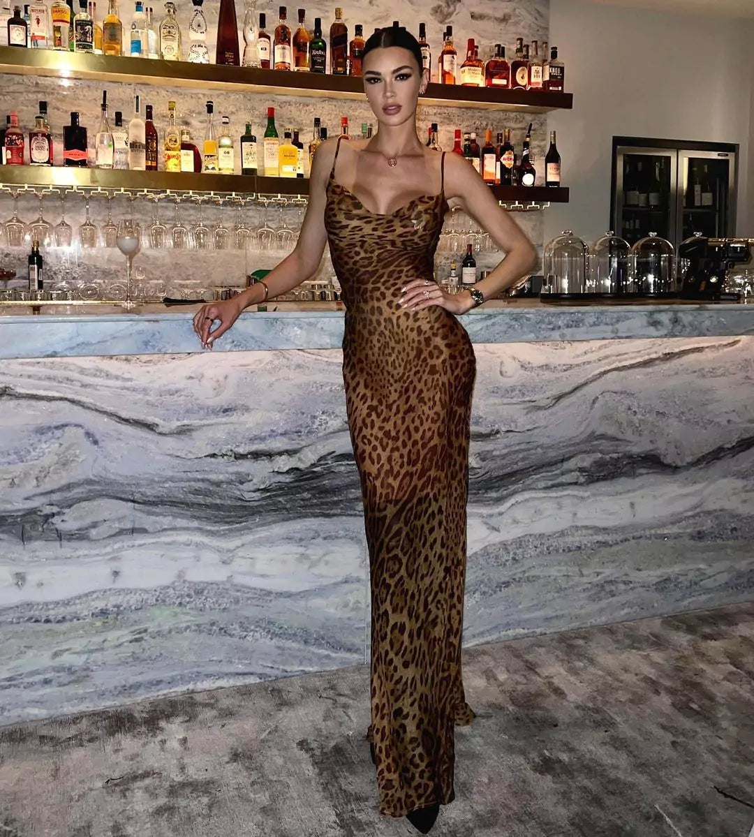 A woman making a style statement in a leopard print dress posing in front of a bar.