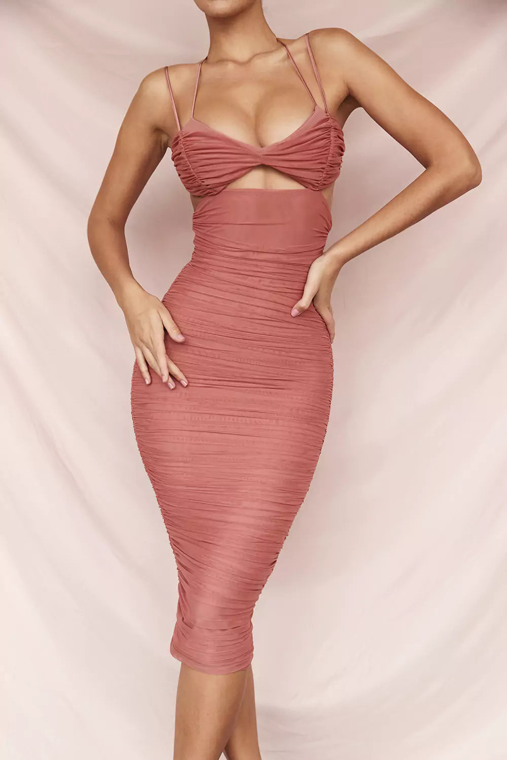 The model is wearing a pink bandage midi dress.