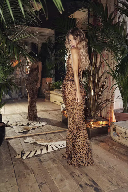 A woman in a leopard print dress standing on a wooden floor.