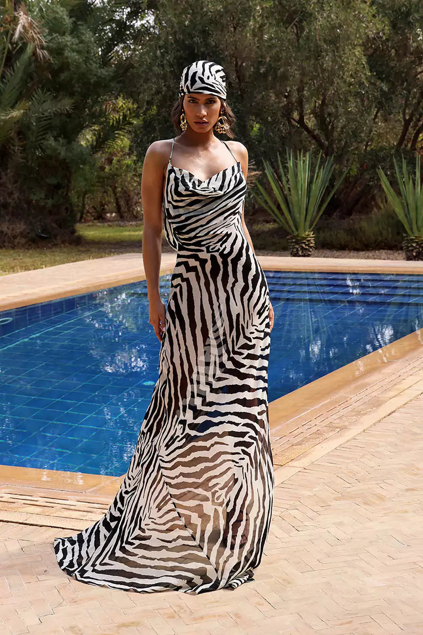 A woman in a zebra print dress standing next to a pool.