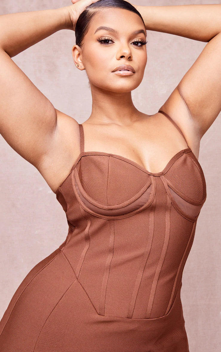 A woman in a brown bodycon dress posing for a photo.