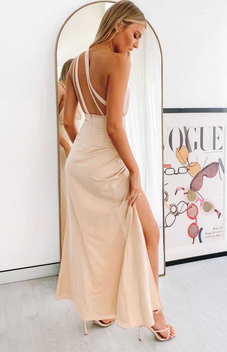 A woman wearing a beige maxi dress in front of a mirror.