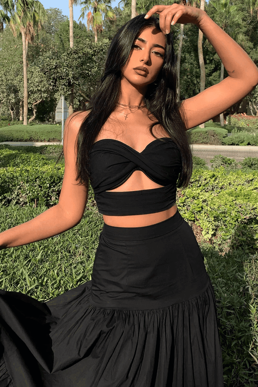 A woman wearing a black crop top and skirt.