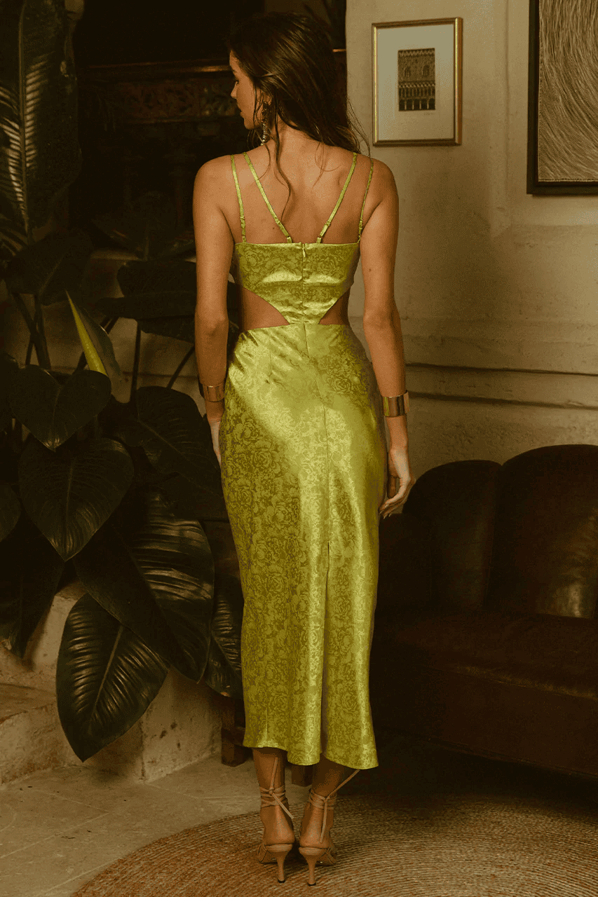 A woman wearing a lime satin dress by Runaway The Label in a living room.